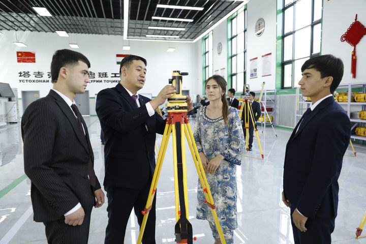 2023年4月12日，在塔吉克斯坦首都杜尚别的鲁班工坊内，来自天津城市建设管理职业技术学院的老师吴正鹏（左二）向学生讲解测绘仪器使用方法。新华社发（奥斯帕诺夫摄）