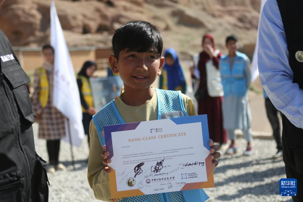 6月16日，在阿富汗巴米扬省的巴米扬大佛遗址区，参加“馕课”的当地学生穆罕默德·扎伊德展示荣誉证书。新华社发（塞夫拉赫曼·萨菲摄）