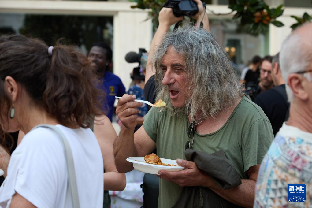 6月13日，一名男子在意大利布林迪西参加集会现场的义餐活动。新华社记者 孟鼎博 摄