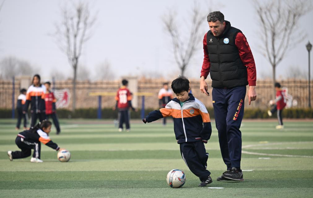 亚历山大·潘蒂奇（右）在天津市静海区华康街道第一小学指导小球员进行足球盘带（3月6日摄）。新华社记者 孙凡越 摄