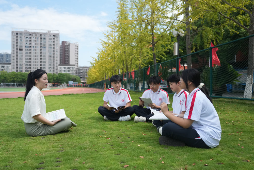 ↑龚佳颖（左）与学生在校园里交流。