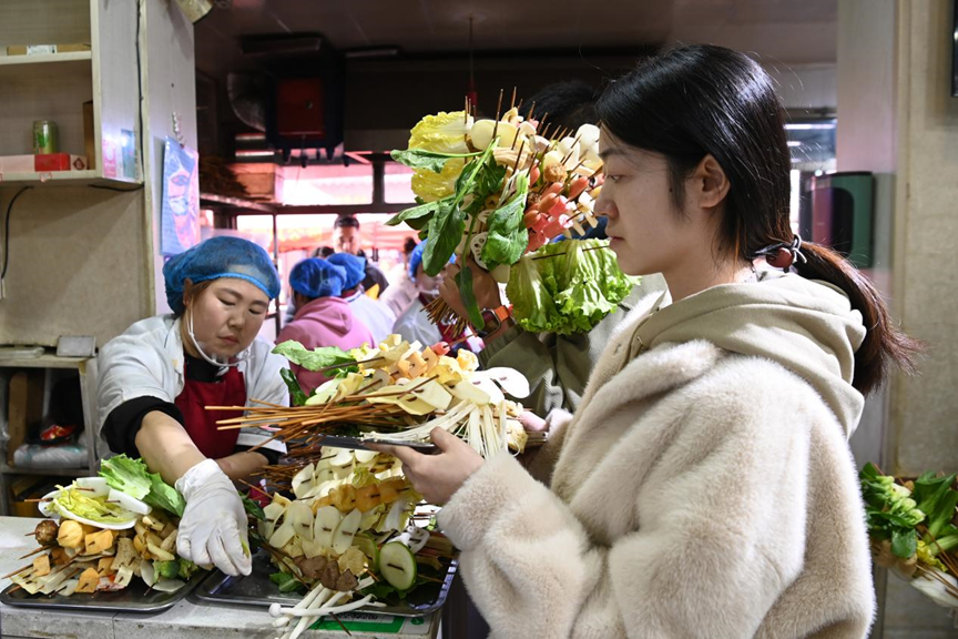 游客挑选好麻辣烫菜品后排队等待加工。新华社记者 范培珅 摄