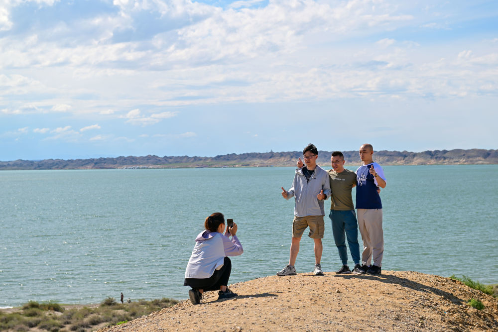 游客在新疆阿勒泰地区福海县乌伦古湖合影留念（7月21日摄）。