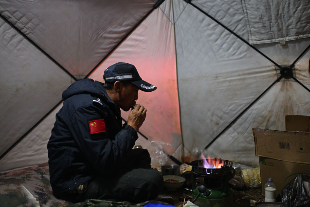 7月8日，在可可西里卓乃湖区域，巡山队员尼玛扎西在帐篷里吃晚饭。新华社记者 张龙 摄