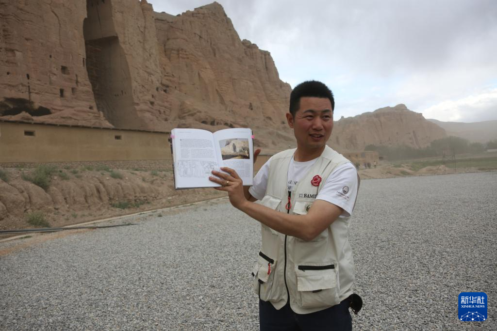 6月15日，在阿富汗巴米扬省的巴米扬大佛遗址区，中国学者邵学成展示书中记载的巴米扬大佛相关内容。新华社发（塞夫拉赫曼·萨菲摄）