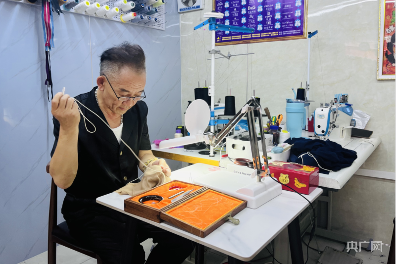 徐春元为顾客修补衣服（央广网记者 褚夫晴 摄）