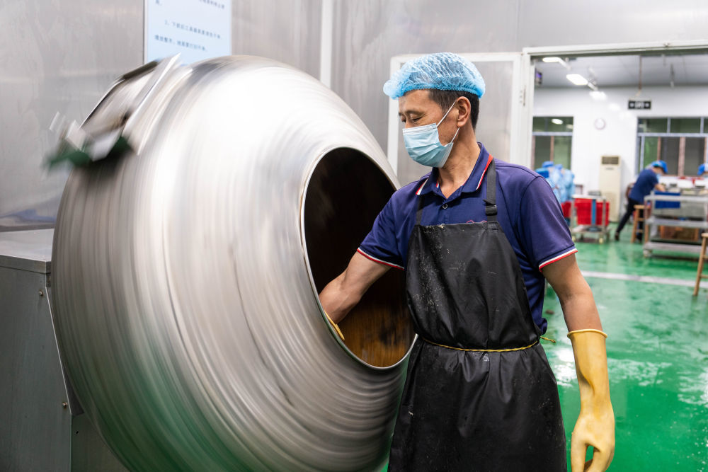 6月5日，在浏阳市关口街道道源湖村一家粽子生产车间，工人在搅拌糯米。