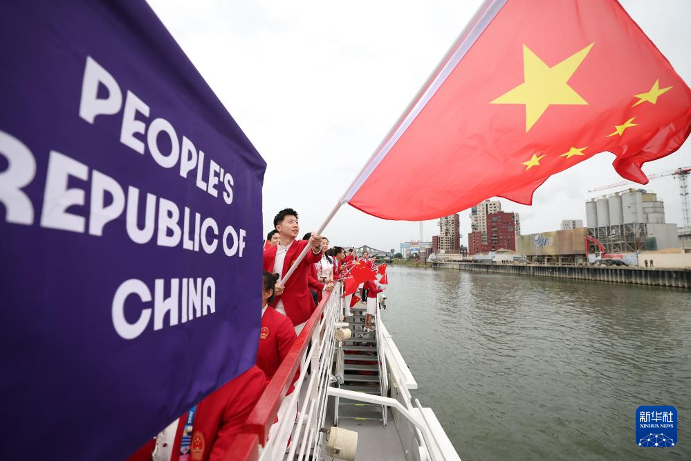7月26日，中国体育代表团旗头乒乓球选手马龙（前）在开幕式前挥舞国旗。新华社