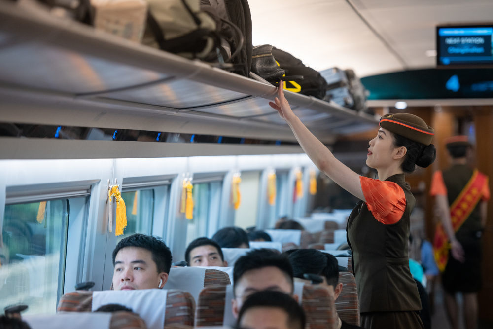 ↑6月15日，在武汉至深圳北的G875次列车上，乘务员在整理行李架。
