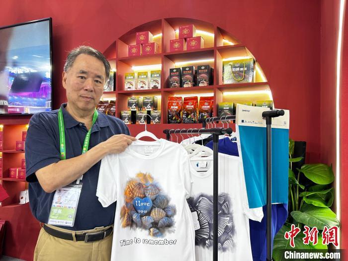 图为台商张建农展示从台湾引进的环保咖啡纱纺织面料制成的海南旅游印花T恤。　中新社记者 符宇群 摄