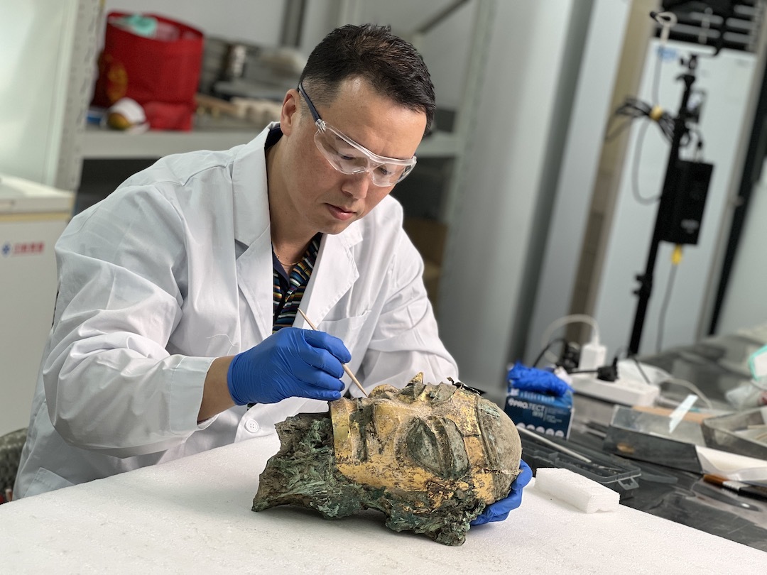 上博青铜器修复及复制技艺传承人张珮琛对金面具笄发青铜人头像进行清理与整形