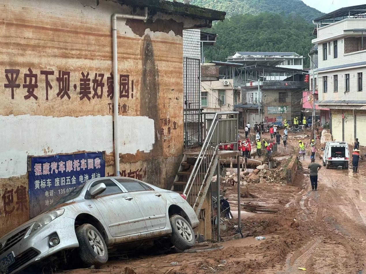 下坝乡街头，一辆汽车被冲倒在路边。