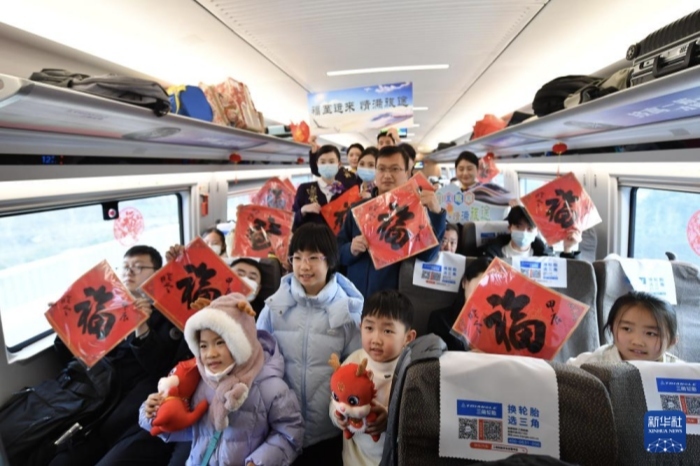 1月26日，邪在由北京北站领往太仓的G8981次列车上，北京客运段的职责主说主员与送到“福”字的旅客折影。（图源：新华网）