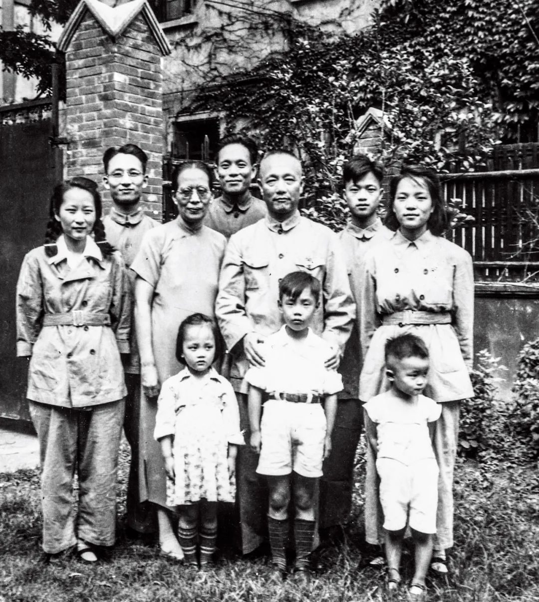 1950年，何家在上海愚园路俭德坊2号前留影。从左至右，前排为：何敏、何仲山、何迪；后排为：缪希霞、何康、陈坤立、何世庸、何遂、何达、何嘉。