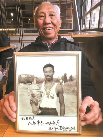 程骏迪手捧年轻时的夺冠照。解放日报 图