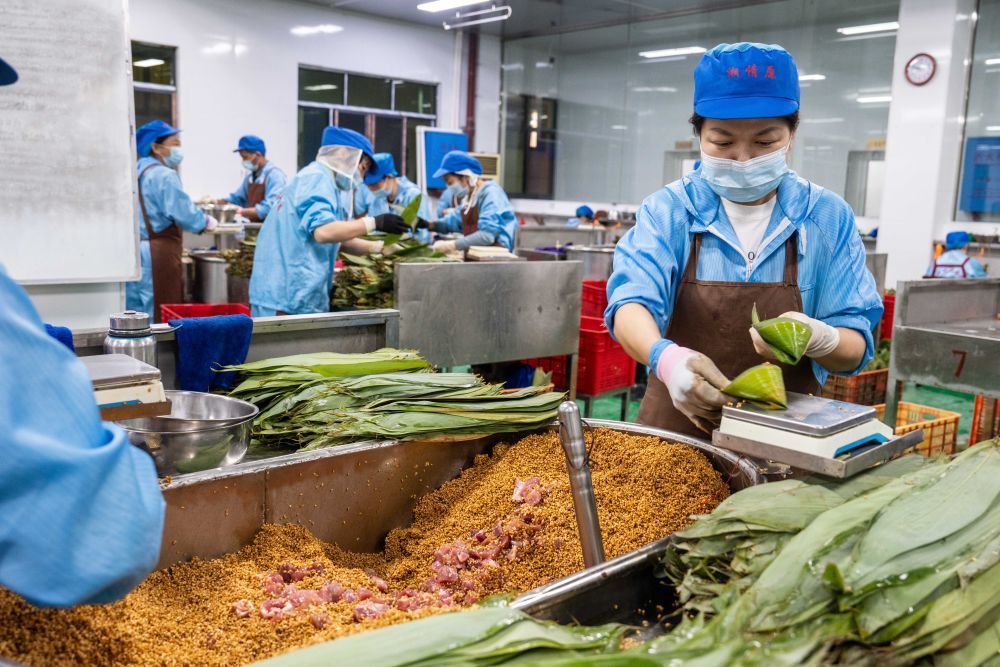6月5日，在浏阳市关口街道道源湖村一家粽子生产车间，工人给粽子称重。