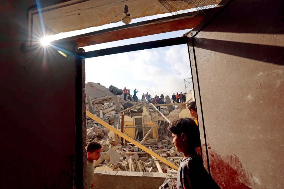 4月21日，在加沙地带南部城市拉法，人们聚集在以色列袭击过后的废墟上。图/视觉中国