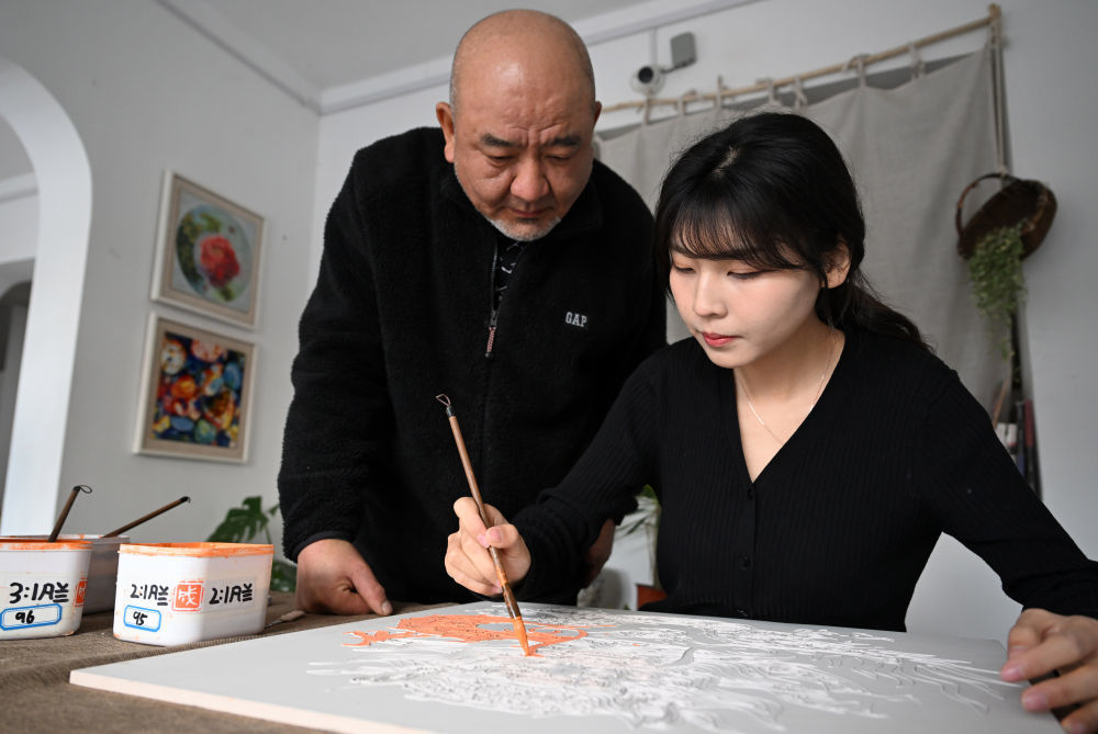 12月3日，在洛阳花城美陶工作室，成果（右）在父亲成永胜的指导下施釉。