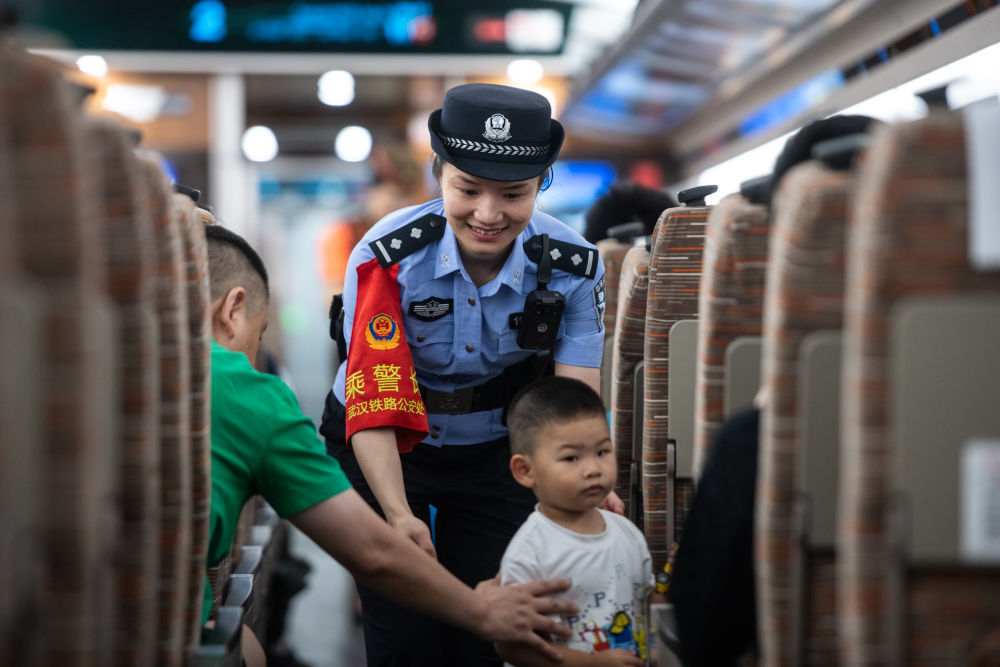 ↑6月15日，在武汉至深圳北的G875次列车上，乘警在引导小朋友回到座位。
