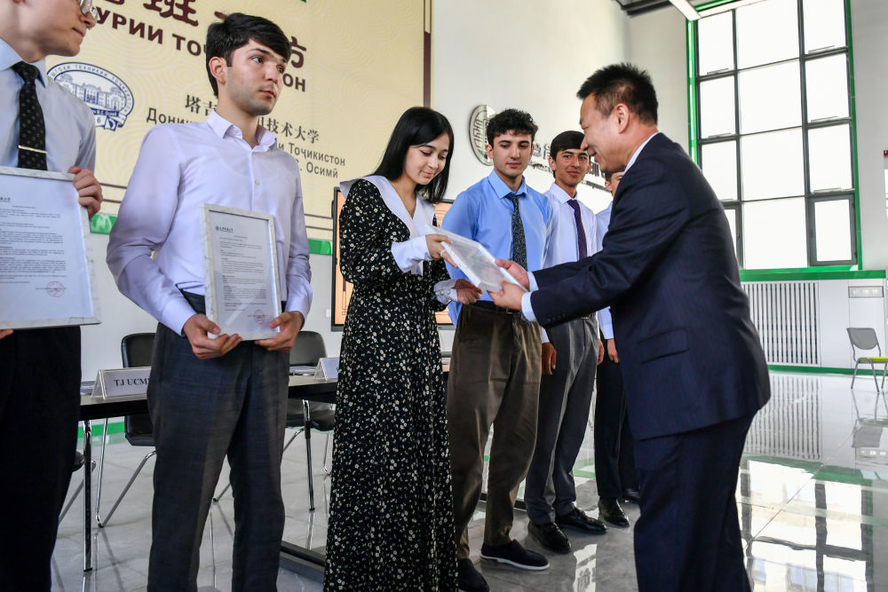 ↑7月3日，在塔吉克斯坦首都杜尚别的鲁班工坊，来自天津城市建设管理职业技术学院的负责人为赴华留学生颁发录取通知书。