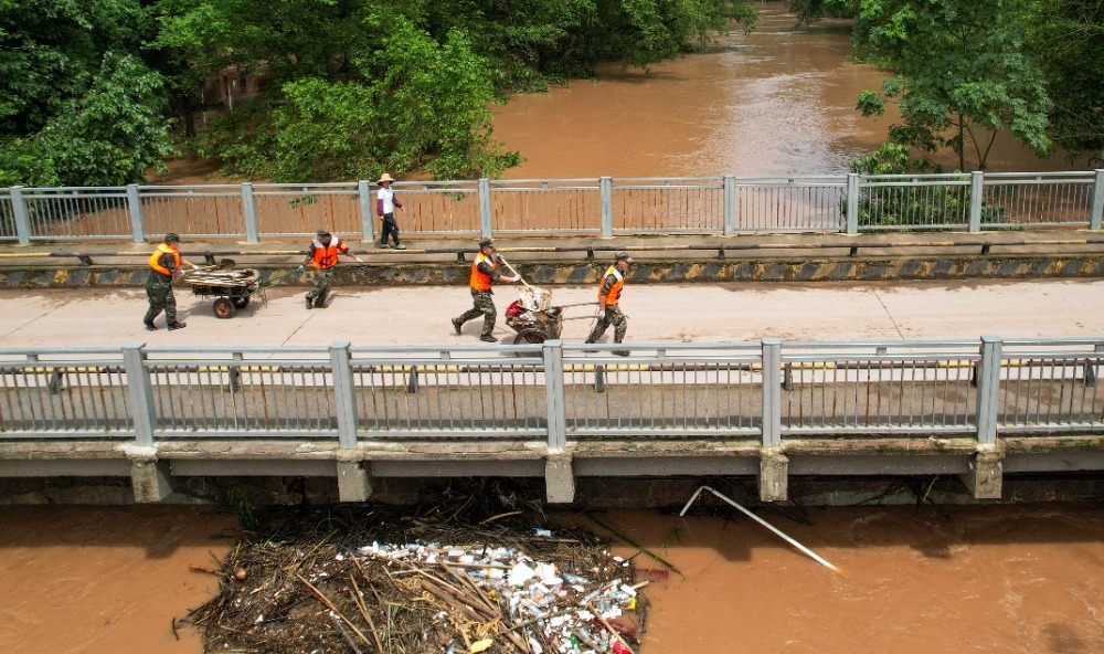 ▲7月12日，垫江县杠家镇龙凤社区，武警官兵们正在转运垃圾。通讯员 龚长浩 摄