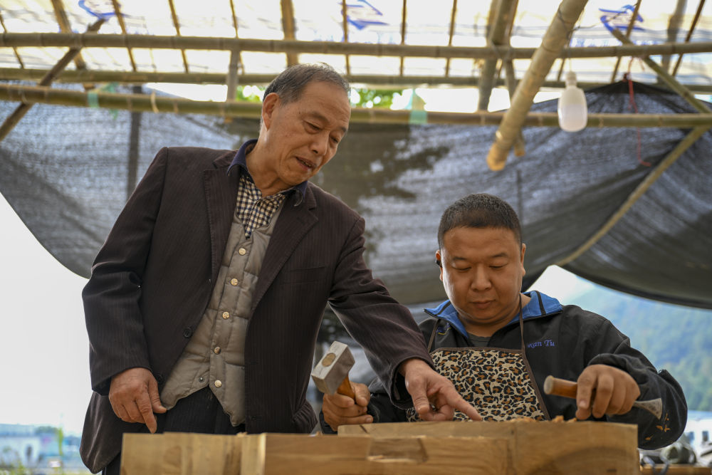 11月22日，在浙江临海汇溪镇浚头村，黄大树（左）与木雕师傅探讨花纹样式。