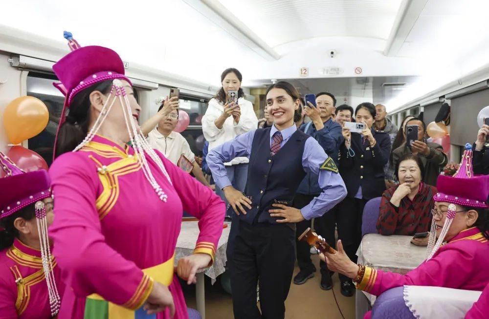 在由喀什开往成都西的列车上，艾尔开牙·多力开与民间艺人一起为旅客跳舞。