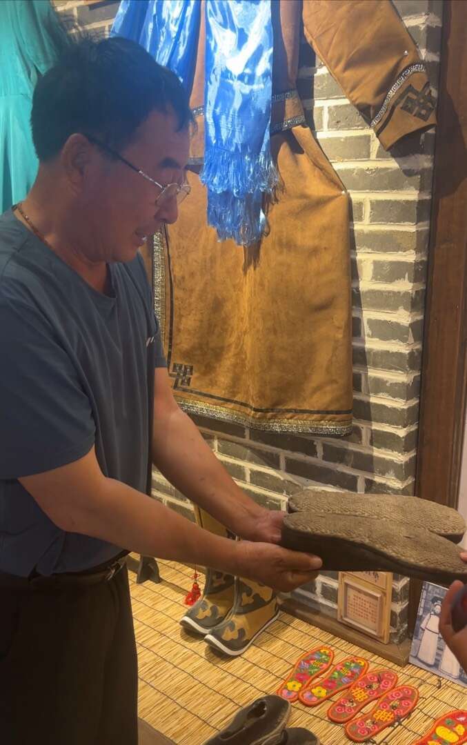 6月28日，在小庙子村博物馆，武凤山拿起便脚鞋向记者展示。中青报&middot;中青网记者 王喆/摄