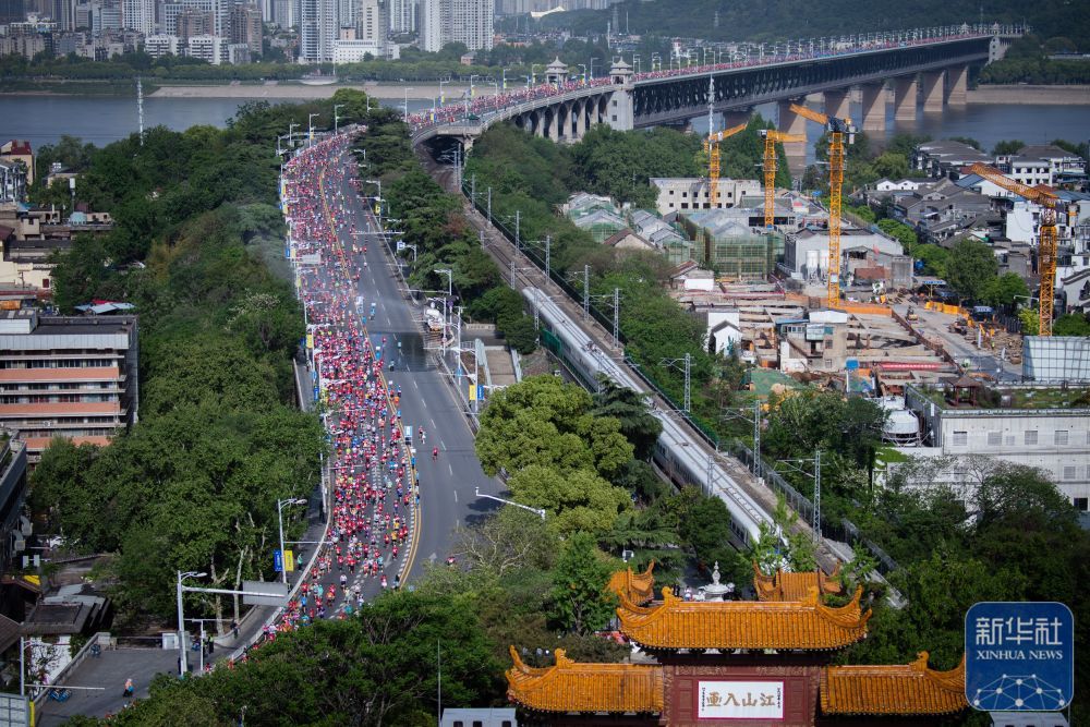 ↑2023年4月16日，参赛选手经过黄鹤楼。 当日，2023武汉马拉松比赛鸣枪开跑，共吸引来自国内外约2.6万名选手参赛。 新华社记者 伍志尊 摄