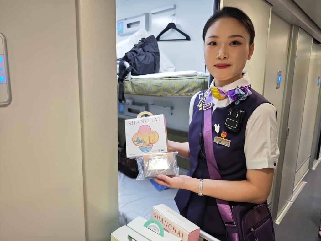 6月15日，乘务员在香港西九龙至上海虹桥D908次高铁动卧列车上展示为首班车旅客准备的纪念品。新华社记者 褚萌萌 摄
