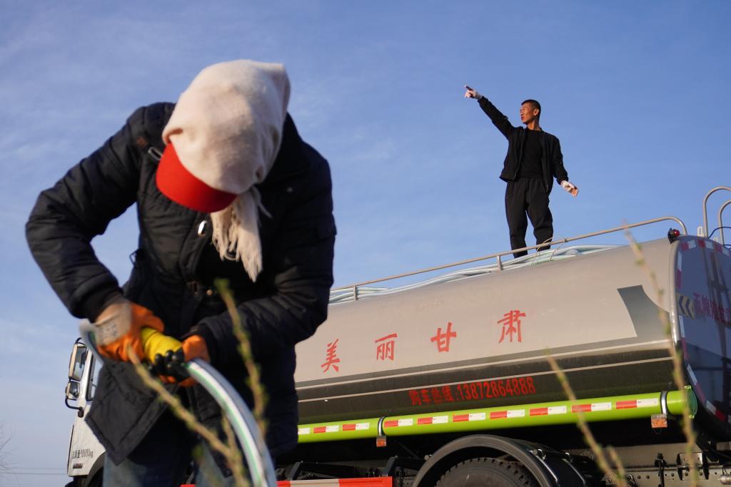 在古浪县八步沙林场眼窝子沙治沙点，郭玺（右）协调林场职工浇水（2024年4月10日）。新华社记者　马希平　摄