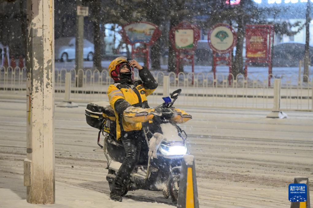 2月20日,一名外卖员在北京市大兴区街头拍摄雪景。当日,北京迎来降雪。