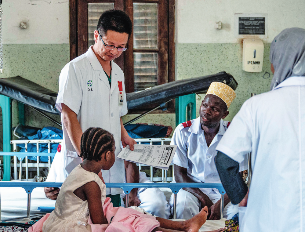 中国援桑给巴尔医疗队队长蒋国庆(左)在坦桑尼亚桑给巴尔的纳兹莫加医院查房(2023 年 12 月 29 日摄)王冠森摄 / 本刊