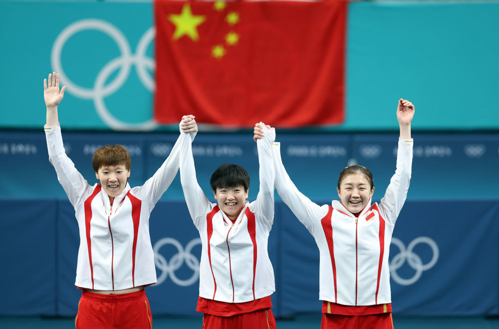 ↑8月10日,由王曼昱、孙颖莎、陈梦(从左至右)组成的中国队在乒乓球女团金牌赛中3比0战胜日本队,实现五连冠。这枚金牌也是中国体育代表团在夏季奥运会上的第300金。