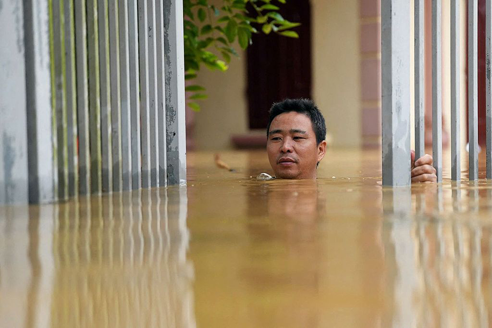 当地时间2024年9月10日，越南，一男子在洪水中前行。视觉中国 图