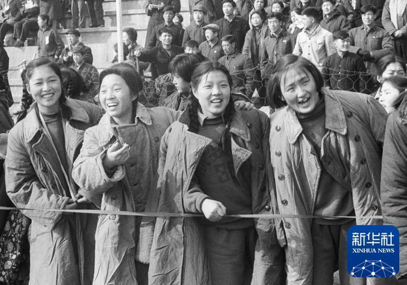 1964年3月8日，北京举行庆祝“三八”杯女子长跑接力比赛，场边身穿军大衣的女青年们观看比赛。