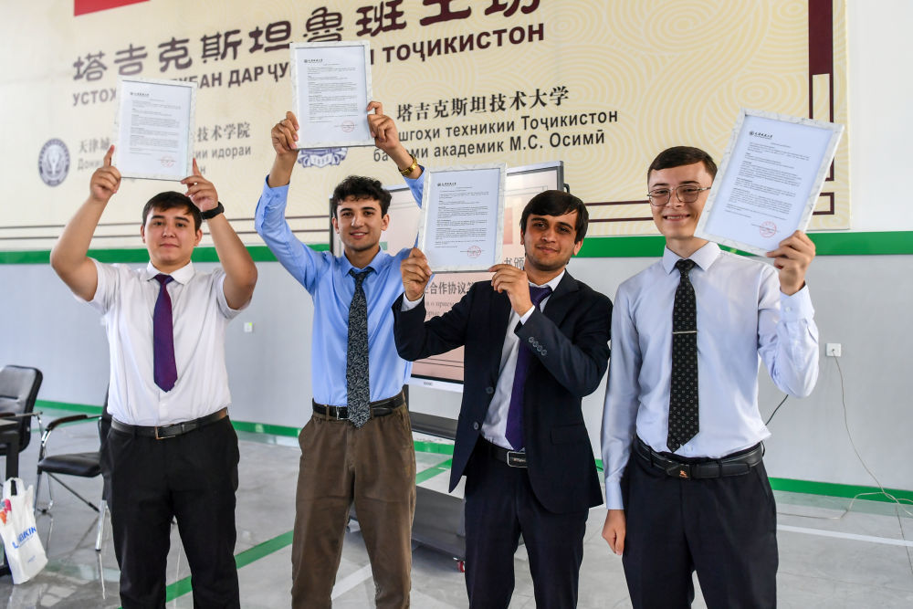 ↑7月3日，在塔吉克斯坦首都杜尚别的鲁班工坊，塔吉克斯坦鲁班工坊赴华留学生展示录取通知书。