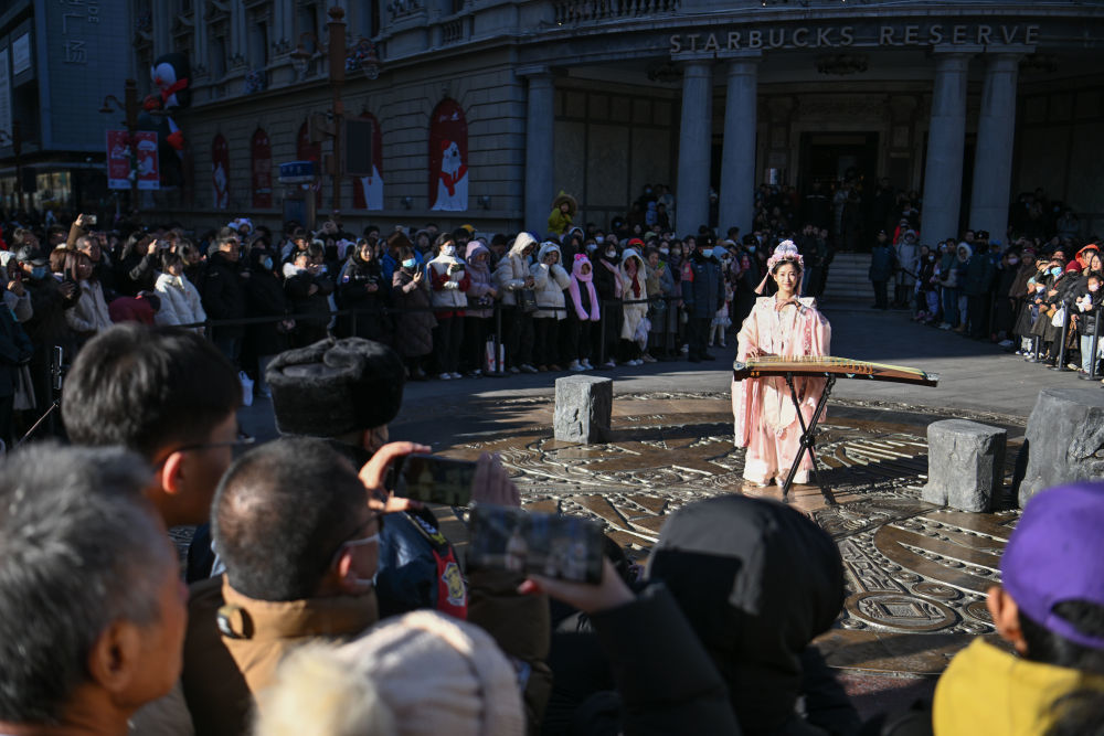 ↑古筝表演者在天津金街步行街大铜钱广场演出（12月21日摄）。