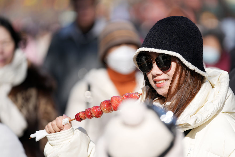2月12日，游客在哈尔滨百年老街中央大街品尝草莓冰糖葫芦。新华社记者 王建威 摄
