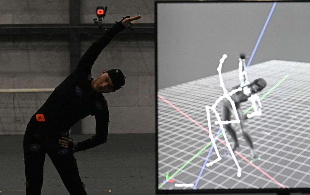 动捕演员马鑫琪在动作捕捉棚内做动作时，一个做着相同动作的虚拟角色在电脑上实时生成（4月23日摄）。