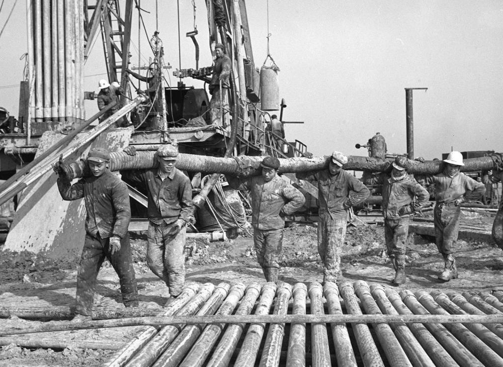 1971年，大庆石油会战的标杆队——1202钻井队工人在新油田用人抬肩扛的办法建井场。