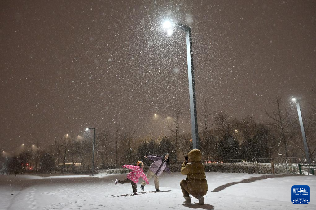 2月20日，在北京市大興區(qū)西紅門生態(tài)公園內(nèi)，一位母親在雪中給女兒拍照。當日，北京迎來降雪。