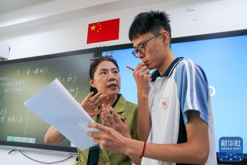 9月3日，在南京市聋人学校，史学军（左）为学生讲解物理习题。