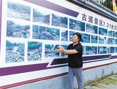 8月21日,水峪嘴村,付宏春站在洪水纪实墙前讲述。