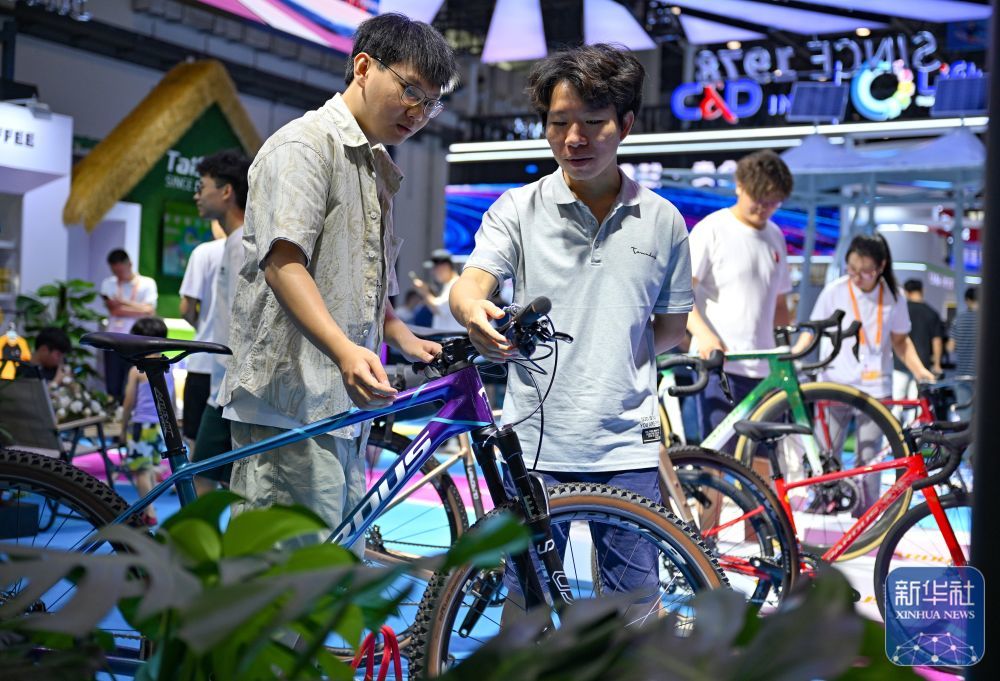 ↑4月17日，参观者在泰山体育展台参观自行车，此品牌是第四次参展消博会。新华社记者 郭程 摄
