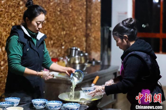 12月20日，西藏芒康，果拉卓玛(左)在为食客盛加加面。 中新社记者 薛蒂 摄