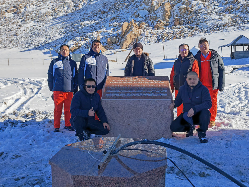 执行中吉乌铁路可行性研究的中铁第一勘察设计院专家团队成员在吉尔吉斯斯坦纳伦州的“中吉友谊井”（前）和纪念石碑旁合影（2022年11月26日摄）。新华社发（中铁第一勘察设计院供图）