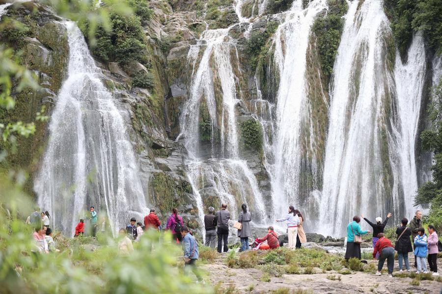 5月1日，游客在贵州省丹寨县龙泉镇排廷村瀑布观赏游玩。新华社发（杨武魁摄）