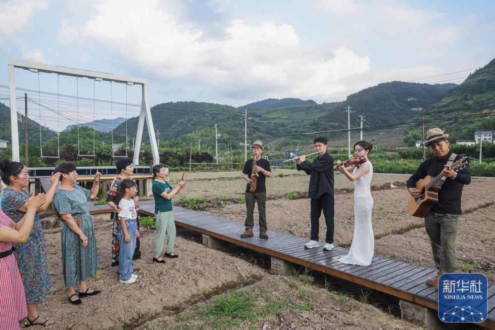 6月15日，三都镇镇头村的村民乐队乐手和杭州师范大学音乐学院的学生（右二、右三）在田间为村民即兴演出。