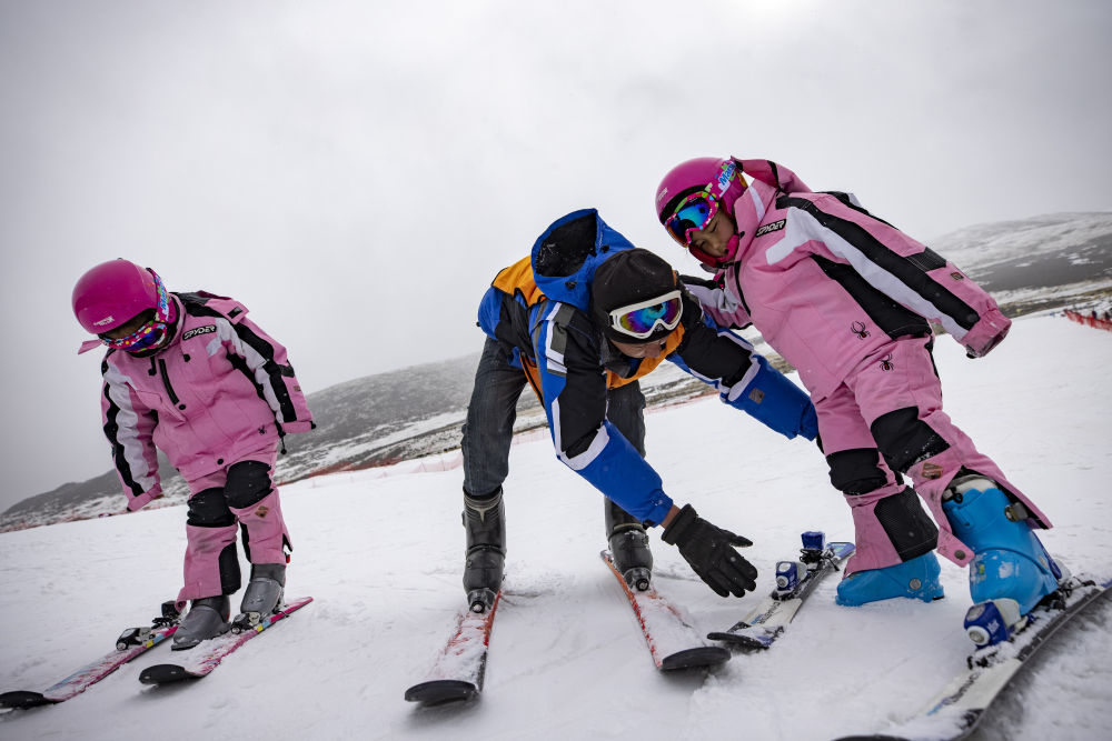 ↑2024年1月27日，在墨多滑雪场，欧珠卓玛（左）、平措卓玛（右）在教练洛桑平措的帮助下学习滑雪。新华社记者 姜帆 摄